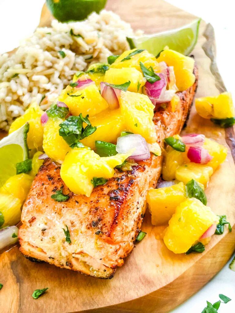 Close view of a piece of Salmon with Mango Salsa on a wood board.