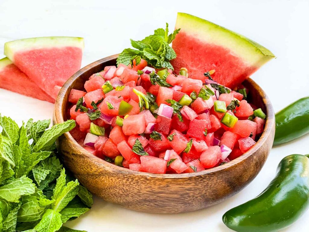 A wood bowl full of Watermelon Salsa on a counter.