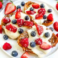 Looking down on a white plate with three Mixed Berry French Toast pieces and fresh berries.