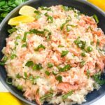 Looking down on a bowl of Salmon Risotto with fresh lemons around it.