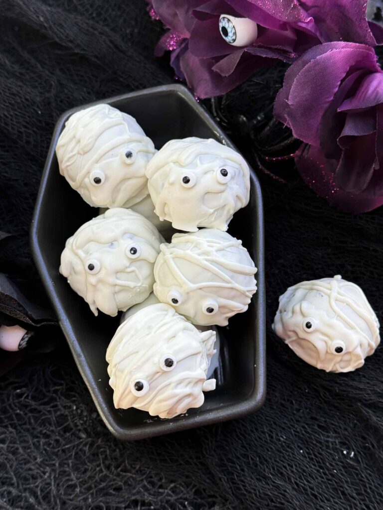 Halloween Mummy Cake Pops stacked in a ceramic coffin.