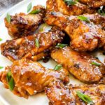 Pin of Thai Chicken Wings on a plate with title at top.