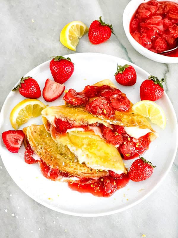 Looking down on a plate of Lemon Strawberry Crepes on a counter.