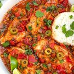 Pin of Chicken Veracruz (Pollo a la Veracruzana) pieces in a bowl with rice.