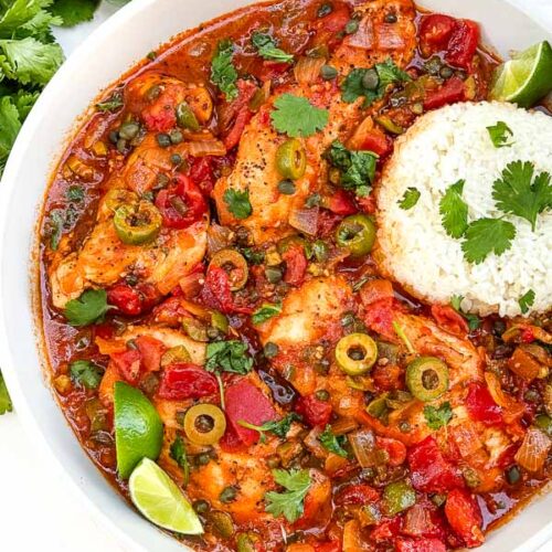 Looking down on Chicken Veracruz (Pollo a la Veracruzana) in a large dish with some rice.