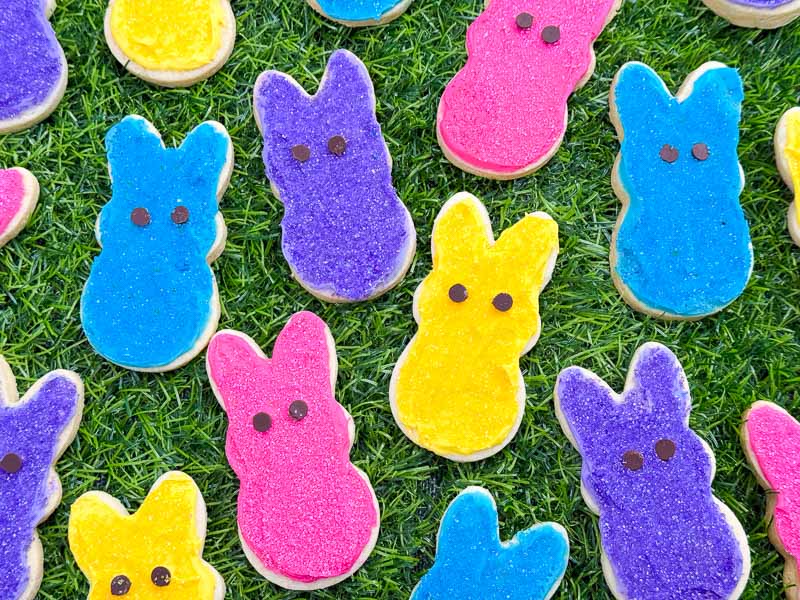 Bright Peeps Bunny Easter Sugar Cookies laid out on grass.