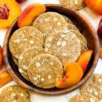 Looking down on a wood bowl full of round Peach Crisp Dog Treats.