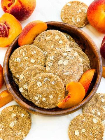 Looking down on a wood bowl full of round Peach Crisp Dog Treats.