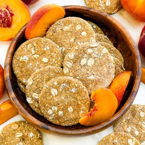 Looking down on a wood bowl full of round Peach Crisp Dog Treats.