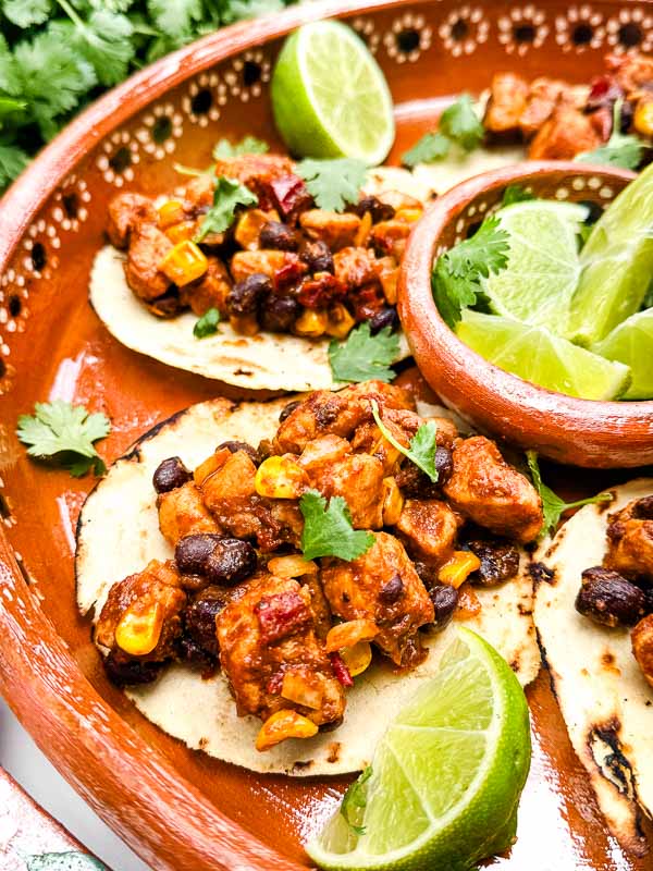 Southwest Chipotle Chicken Tacos in a Mexican dish in a circle with fresh limes.