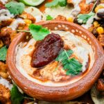A small clay dish full of Homemade Chipotle Crema Sauce with a smoked pepper garnish.