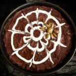 Looking down on a Halloween Spider Bean Dip with a white sour cream web design on a black bean dip and an olive spider.