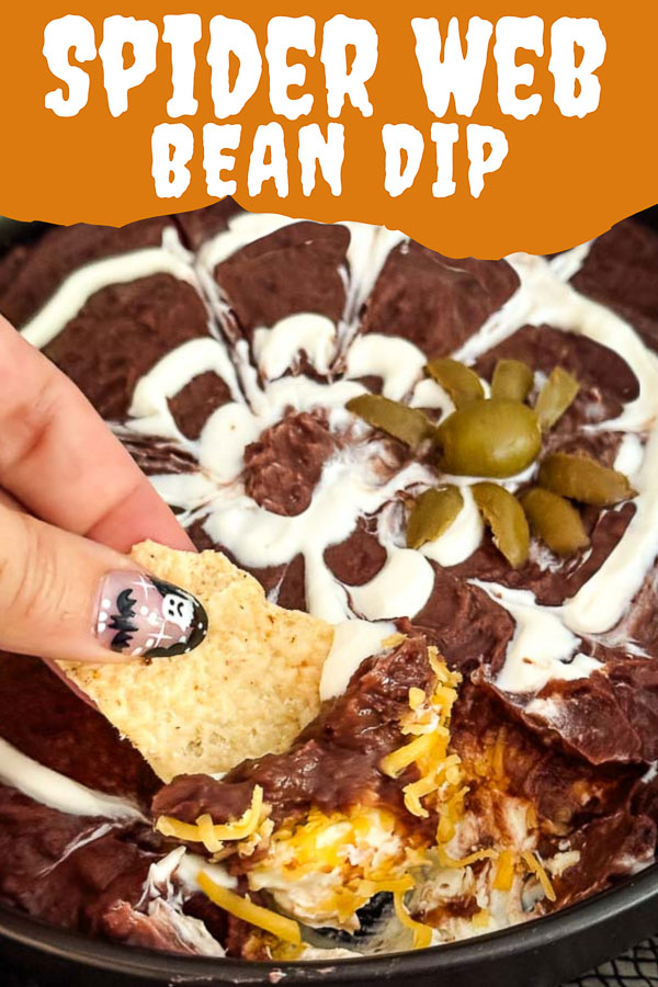 Pin of a hand digging a chip into Halloween Spider Bean Dip.